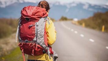 Backpacker walking alone on open road symbolising visa uncertainty or transition period
