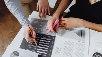 Team analysing workforce data and visa program metrics using reports and highlighters