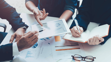 Close-up of business professionals analysing sponsorship visa data on tablet and reports